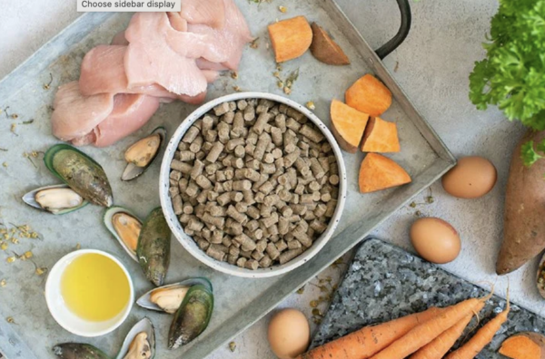 Bowl of cold pressed dog food next to fresh meat, vegetables and muscles